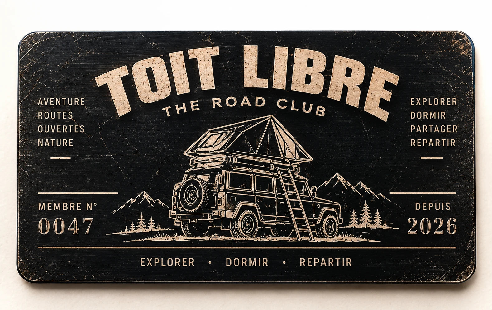 Mockup de face de la carte Toit Libre Road Club en aluminium noir patiné : nom en arc, 4×4 avec tente de toit et échelle, numéro d’illustration 0047 et mention Depuis 2026.